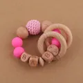 Macro view of silicone beads and wooden blocks spelling BABY on the infant teething ring - Rose Red
