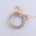 Set di cinque braccialetti in silicone glitterato oro con fiocco in nastro champagne - Champagne