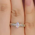 Detailed close-up of a luxury oval opal ring with pavé diamond band in 18k gold finish - US 6 / Gold White Opal