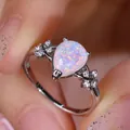 Pear-shaped opal ring with floral white stones on silver band held by hand - US 6 / Platinum White Opal