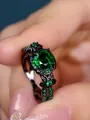 Macro detail of vintage black metal ring featuring a large round green zircon center stone - Black Gold Green Zirconia