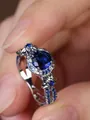 Detailopname van de zilveren ring met ronde blauwe steen en florale micro-pave aan de zijkant - Maat 5 / Witgoud Met Blauwe Zirkoon