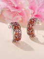Détail des boucles d'oreilles C argentées avec zircone orange sur fond floral rose - Plaqué Platine Zircone Rouge