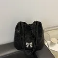 Schwarze Umhängetasche mit Faltenoptik und silbernem Schmetterling auf Ledersofa - Schwarz