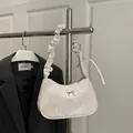 Chic beige underarm bag with pleated strap and silver bow detail for winter fashion - White