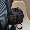 Bolso cubo negro minimalista con cordón y dos bolsillos frontales con detalles plateados - Negro