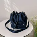 Navy blue nylon bucket bag with dual front pockets and drawstring closure in studio lighting - Blue