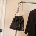 Fashionable black sequin bucket bag with bright yellow drawstring and gold chain strap - Black