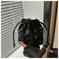 Close-up of shiny black sequin bucket bag with drawstring handle and glitter texture - Black