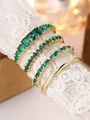 Macro shot of gold rings set with deep green gemstones on white lace textured display - Gold (Green Zirconia)