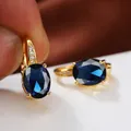 Makroaufnahme ovaler blauer Zirkonia-Ohrringe in Goldfassung mit Akzenten - Gold Königsblau