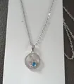 Macro view of silver snowflake pendant with a blue gemstone on a delicate cross chain - Silver Snowflake Round