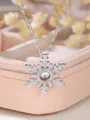 Macro shot of silver snowflake pendant with large sparkling crystal on pink jewelry box - Shimmering Snowflake