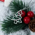 Macro shot of a sparkling silver Christmas tree pendant with green gems on a snowy branch - Silver 6-Green Zircon Tree