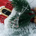 Macro detail of Christmas tree pendant with red and green crystals on snowy background - Silver Orange and Green Zircon Tree