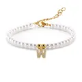 Detail van parelarmband met goudkleurige letter W hanger en glanzende kristallen - Letter W