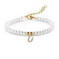 Macro detail van een 3-4mm parelarmband met een gouden letter U hanger en zirkoon - Letter U