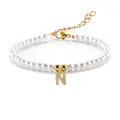 Detail van witte parelarmband met gouden letter N-hanger en glinsterende zirkonen - Letter N