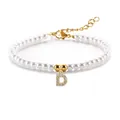 Detail van parelarmband met sprankelende letter D-bedel en gouden karabijnsluiting - Letter D