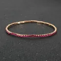 Glitzerndes roségoldenes elastisches Armband mit pinken Strasssteinen auf dunklem Grund - Lila