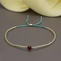 Detail of red faceted gemstone with bohemian yellow seed beads on blue braided cord - Cyan Rope/Deep Red Gem/Green Yellow Bead(BR0114)