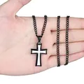 Detail of a minimalist black and white titanium steel cross pendant held in hand - Black Border White Enamel