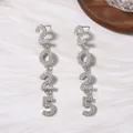 Foto macro de pendientes largos plateados 2025 con pedrería sobre fondo de mármol - Estilo de Número 2025 / Plata con pedrería blanca