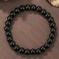 Dettaglio del bracciale di perline nere con motivi lunari su uno sfondo in legno rustico - Stile Pietra Nera Lucida (ZJ14158)