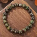 Close-up of natural dragon blood stone beaded bracelet on rustic wood grain surface - Unakite Style (ZJ14151)
