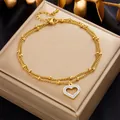 Detalle de una tobillera doble dorada con colgante de corazón y cristales brillantes - Estilo de Corazón con Circonita de Doble Capa (B949)