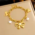 Dettaglio di bracciale dorato a strati con ciondoli a libellula, cuore e farfalla di perla - Stile Multi-Charm Oro (B1578)