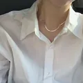 Collier nœud en argent S925 avec chaîne serpent porté sur une chemise blanche - Collier Noeud / Argent 925
