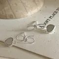 Detailopname van zilveren strikoorbellen met hartvormige hangers van parelmoer - Zilver