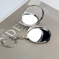 Mini specchio da trucco rotondo in metallo argento pieghevole con portachiavi su sfondo rivista - Rotondo