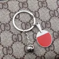 Metallic table tennis racket keychain with red rubber and mini ball on luxury background - Red Table Tennis Paddle And Ball