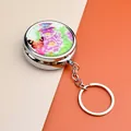 Détail d'un porte-clés boîte à pilules argentée avec motif de pivoine et papillon - Style Pivoine Avec Porte-clés