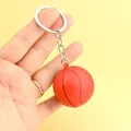 Schlüsselanhänger Basketball in Orange mit Struktur und Silberring auf gelbem Grund - Basketball