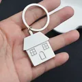 Handheld silver house-shaped metal keychain with reflective finish and house details - House-Shaped / Silver