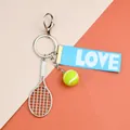 Detail of creative tennis keychain with mini racket, green ball and blue LOVE ribbon strap - Tennis Racket Ball And Blue LOVE Ribbon