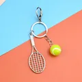 Portachiavi da tennis con pallina gialla e gancio in metallo su uno sfondo sportivo vivace - Racchetta Tennis Palla E Chiusura A Moschettone
