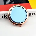 Close-up of rose gold folding compact mirror with a faceted dark blue crystal inlay - Light Blue