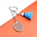 Detail of silver badminton racket and blue shuttlecock keychain on bi-color background - Badminton Racket With Blue Shuttlecock / Blue