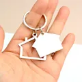 Portachiavi a forma di casa in acciaio lucido tenuto in mano con ciondoli sagomati e traforati - Stile Casa Doppio Strato / Argento