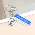 Dettaglio di portachiavi volano con ciondolo segnale stradale blu e anello in metallo - Segnale Mi Manchi con Badminton