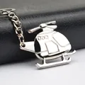 Polished silver metal helicopter keychain with propeller detail on black leather background - Silver