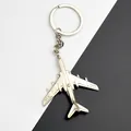 Macro detail of a silver metal airplane keychain with wings on a two-tone background - Silver Airplane Style