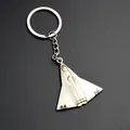 Macro shot of silver metal fighter jet keychain on black textured surface background - J-36 Fighter Jet