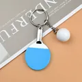 Blue table tennis paddle keychain with white ball and silver metal ring on a brown background - Blue Standard Key Ring Style