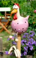 Detailed close-up of a pink resin garden chicken ornament with white polka dots on a wooden pole - Pink