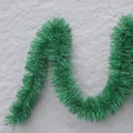 Grüne Weihnachtsgirlande als Weihnachtsdekoration, S-förmig an einer grauen Wand präsentiert - Stil D